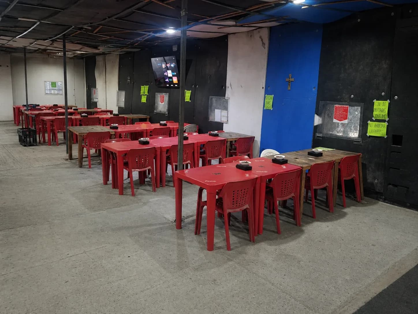 Interior de Lotería Lulú: mesas listas y la pantalla de 65 pulgadas al fondo